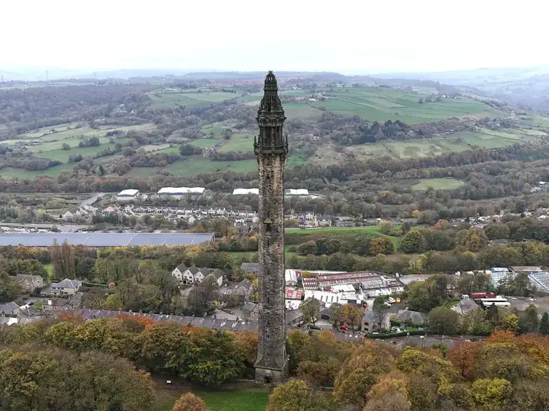 An aerial view of Wainhouse Tower in Halifax, with autumn trees and the Calder Valley beyond
