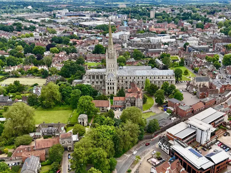 An aerial view of Norwich Cathedral's spire rising above the rooftops of Norwich