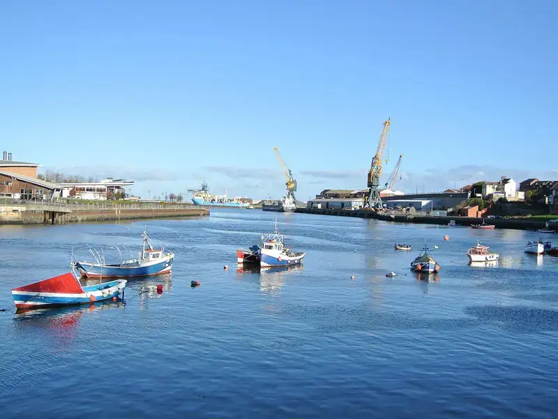 Small fishing boats on the River Wear in Sunderland, with dockside cranes in the distance