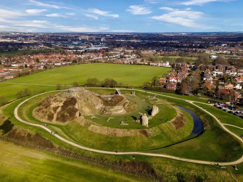 An aerial view of the earthworks and ruins of Sandal Castle, with the houses of Wakefield beyond