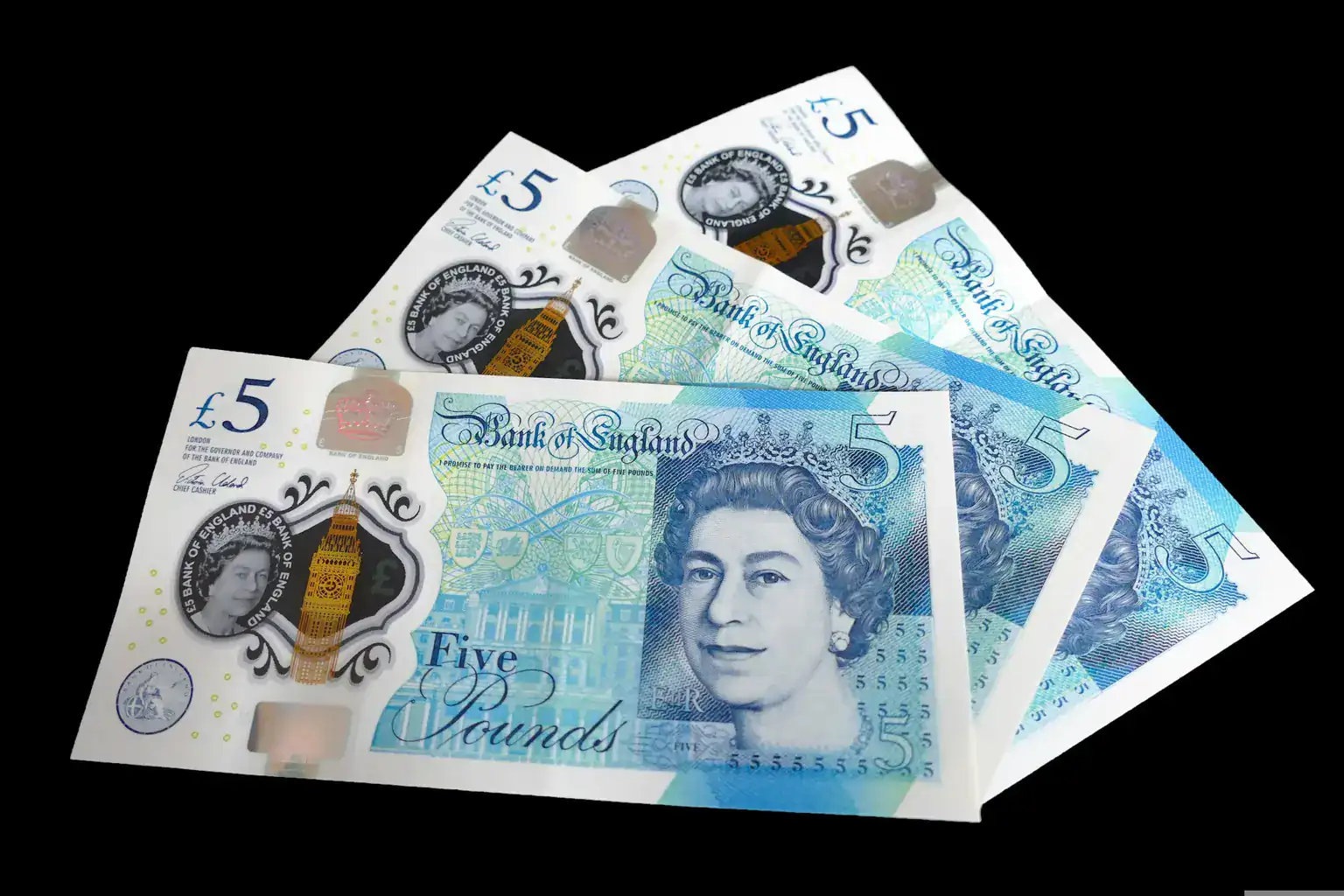 Several British five pound notes fanned out on a black background