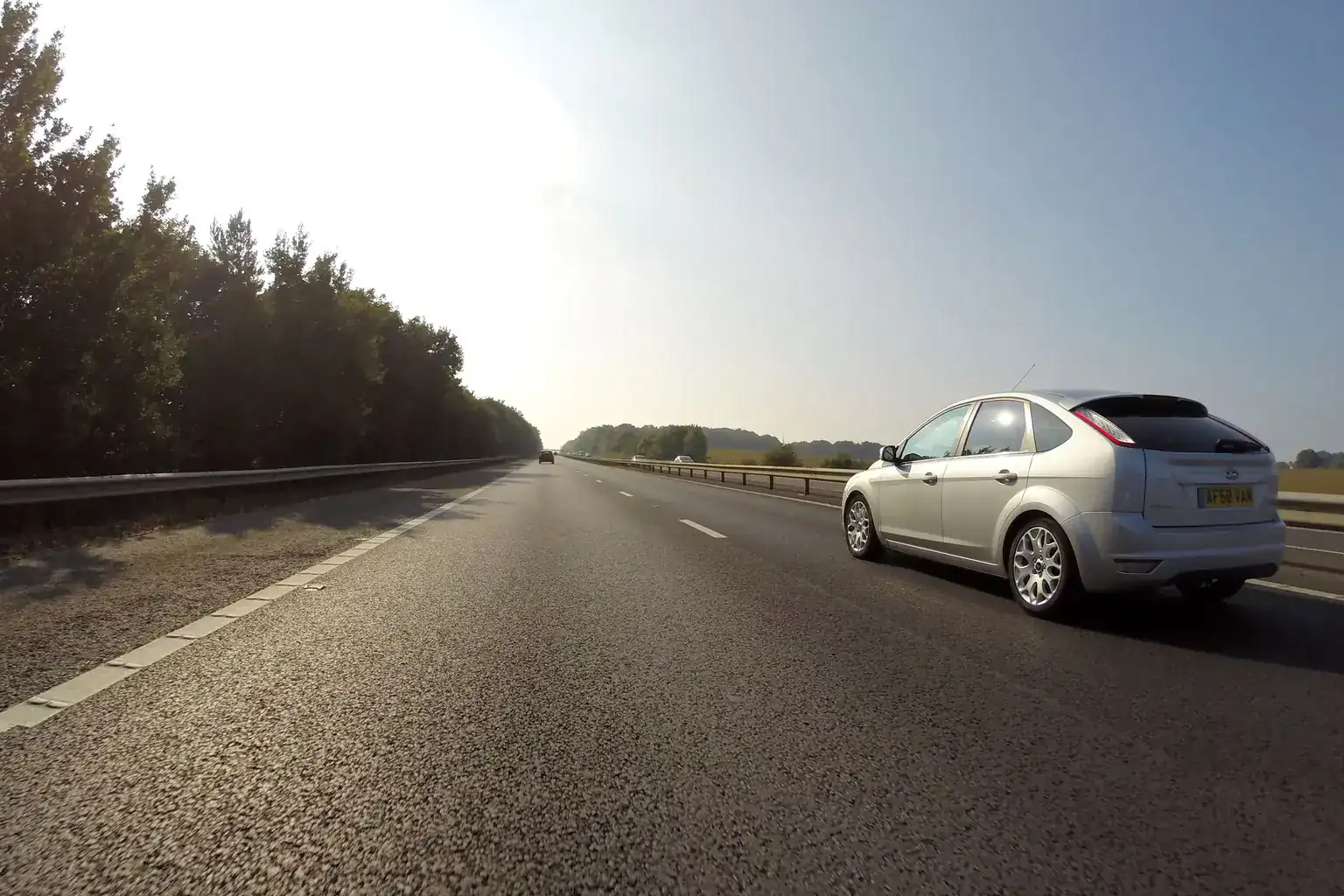 A silver hatchback with a yellow UK number plate driving along a quiet dual carriageway