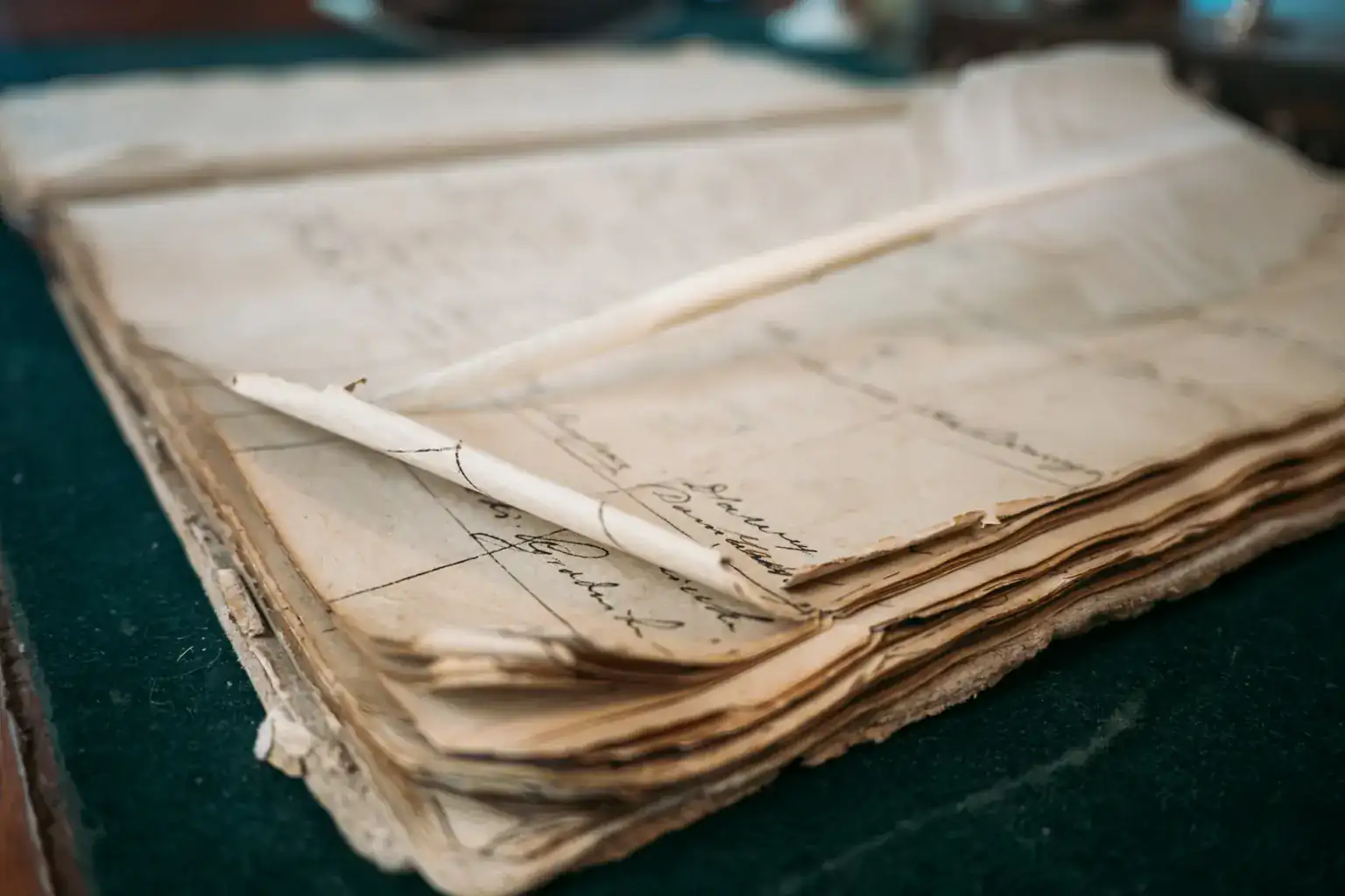A worn, open ledger of handwritten pages with a quill pen resting on top