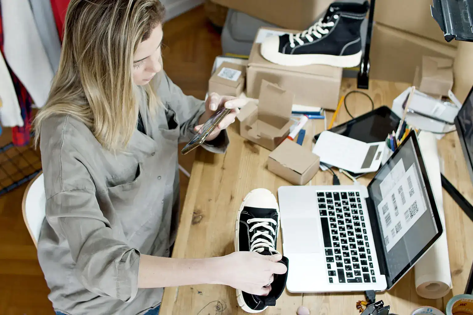 A woman photographs a pair of trainers with her phone to list them for sale online