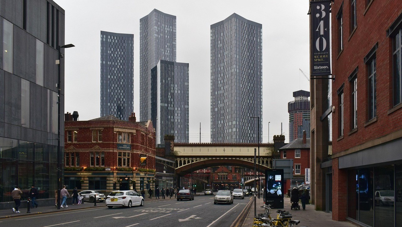 Manchester street scene with modern skyscrapers and a rail bridge during the day – logbook loans Manchester